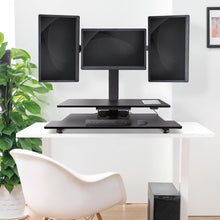 black | three-monitor-arms | Three arm monitor mount Techtonic standing desk converter in an office setting. with screens flipped