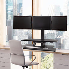 black | three-monitor-arms | Three arm monitor mount Techtonic standing desk converter in an office setting.