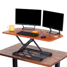 Cherry | The X-Elite Premier corner desk converter in cherry can take your desk from sitting to standing in seconds.